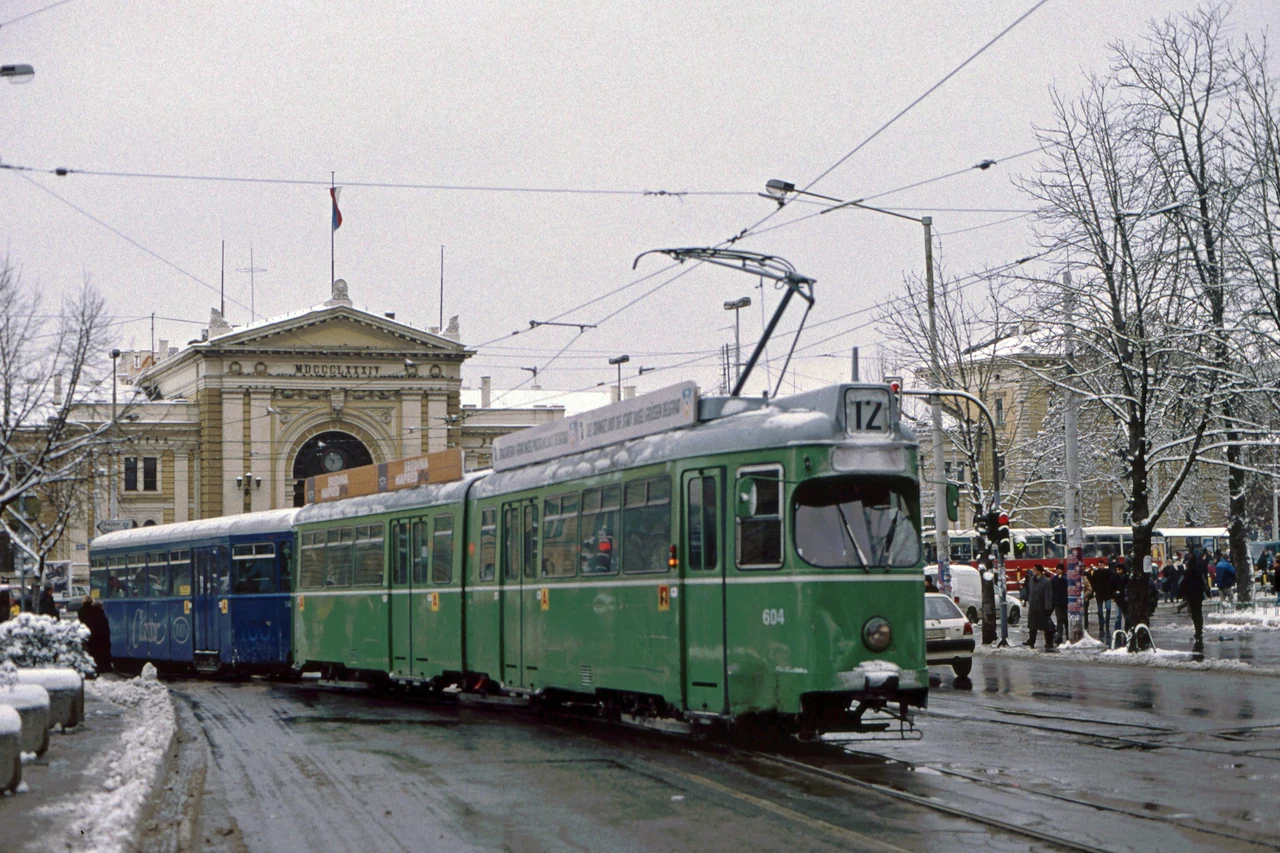 A green tram in front of the railway station.