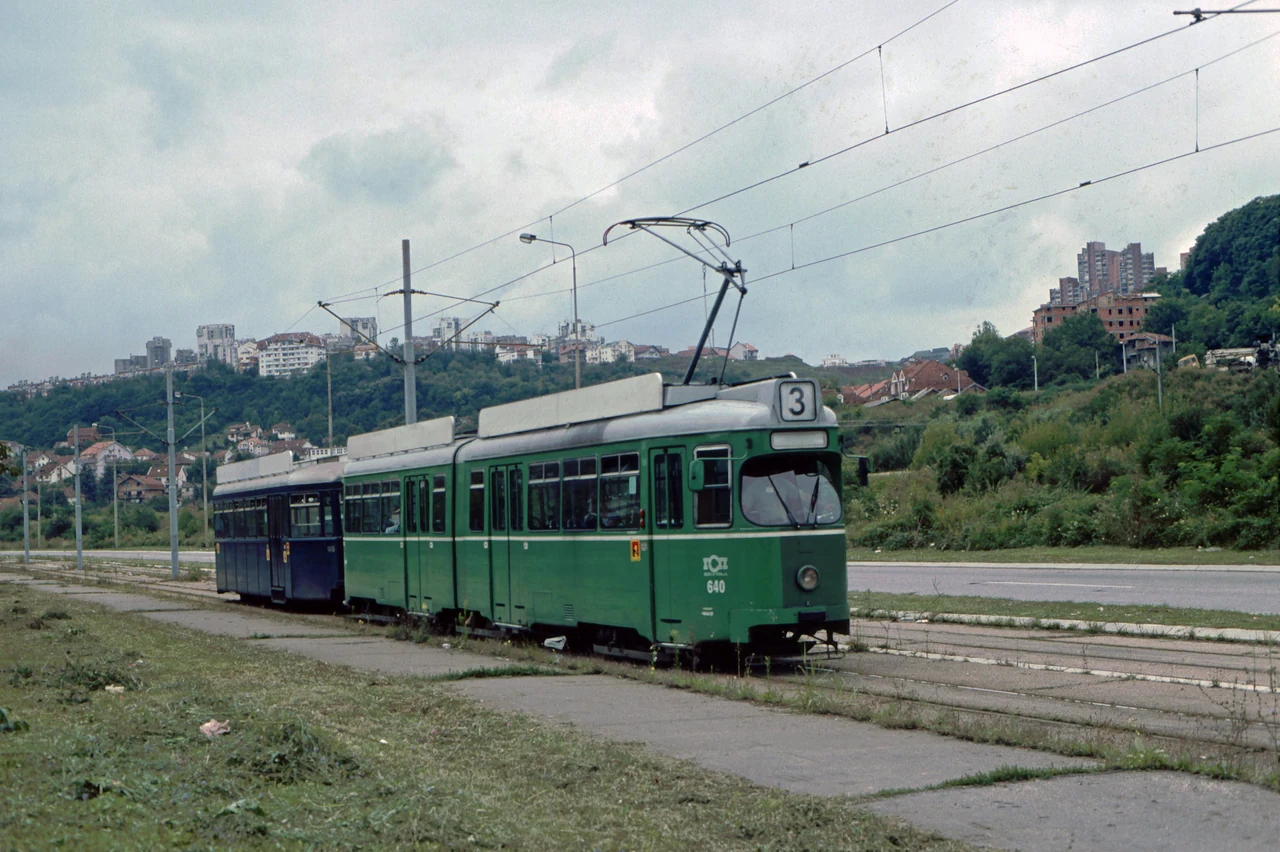 Tram and trailer on an open stretch of track.