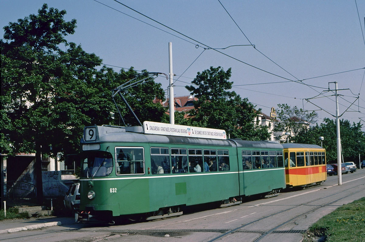 A green tram with a yellow trailer.