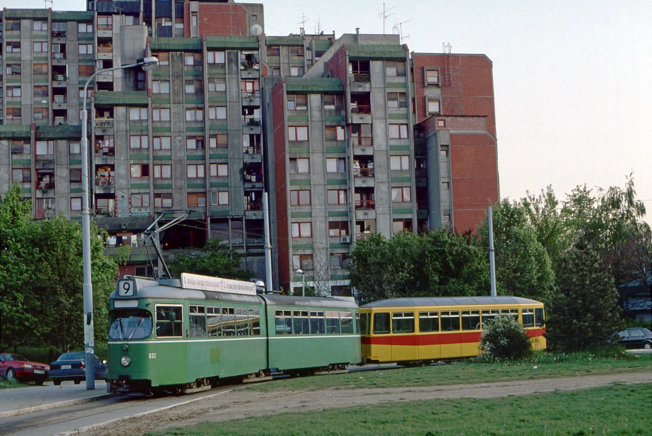 A tram in front of an apartment building.
