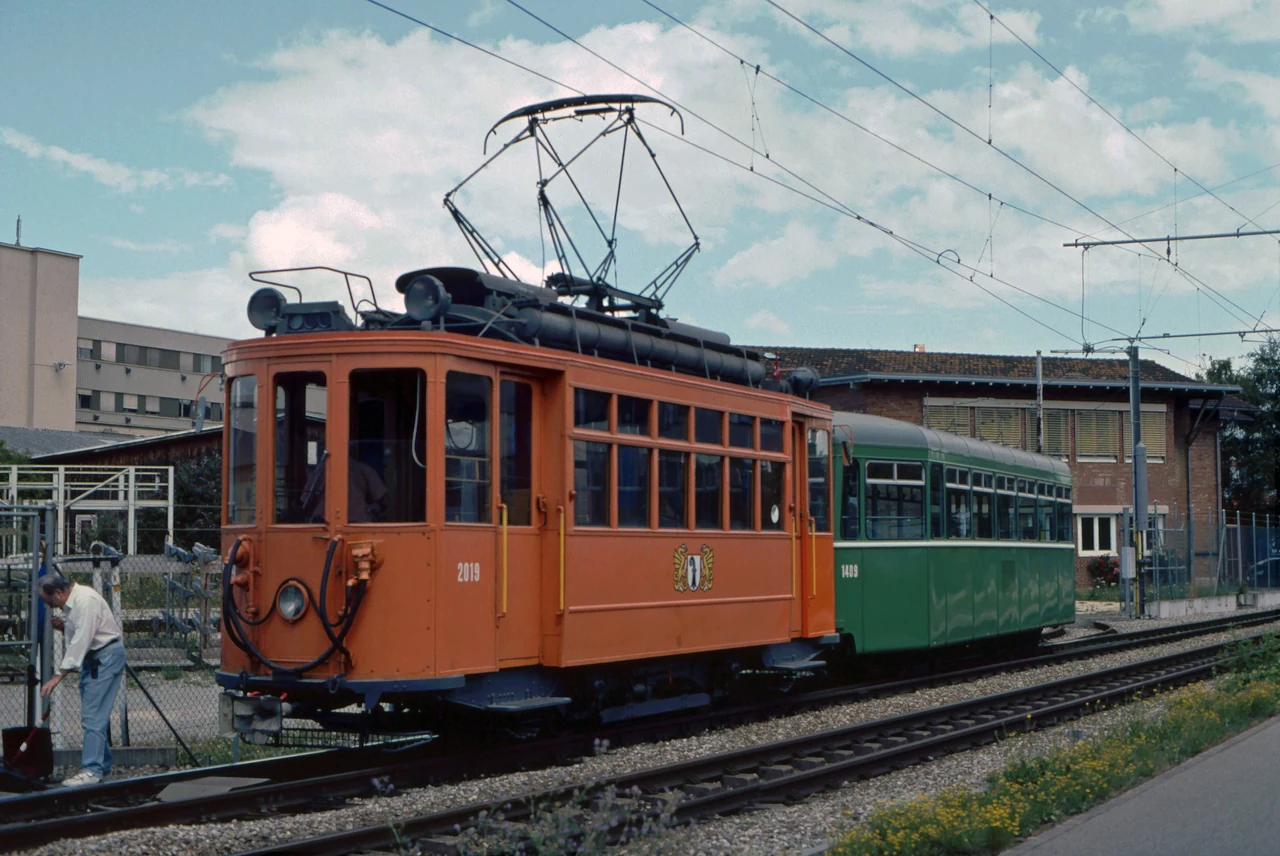 Orange and green trams on the tracks.