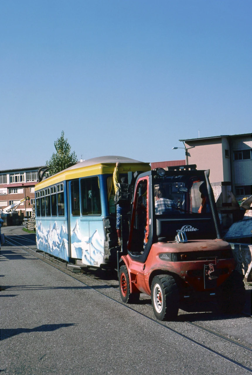 A tram beside a forklift.